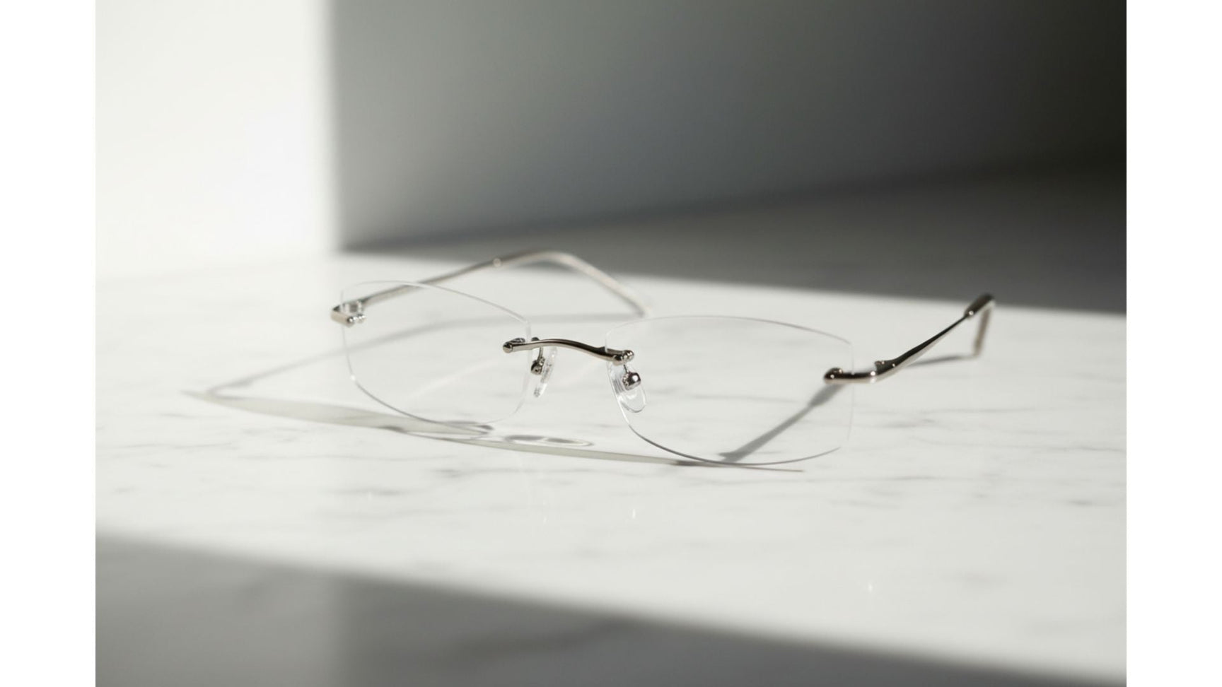 A pair of elegant rimless glasses high prescription lenses, ultra-thin, resting on white marble in soft natural light