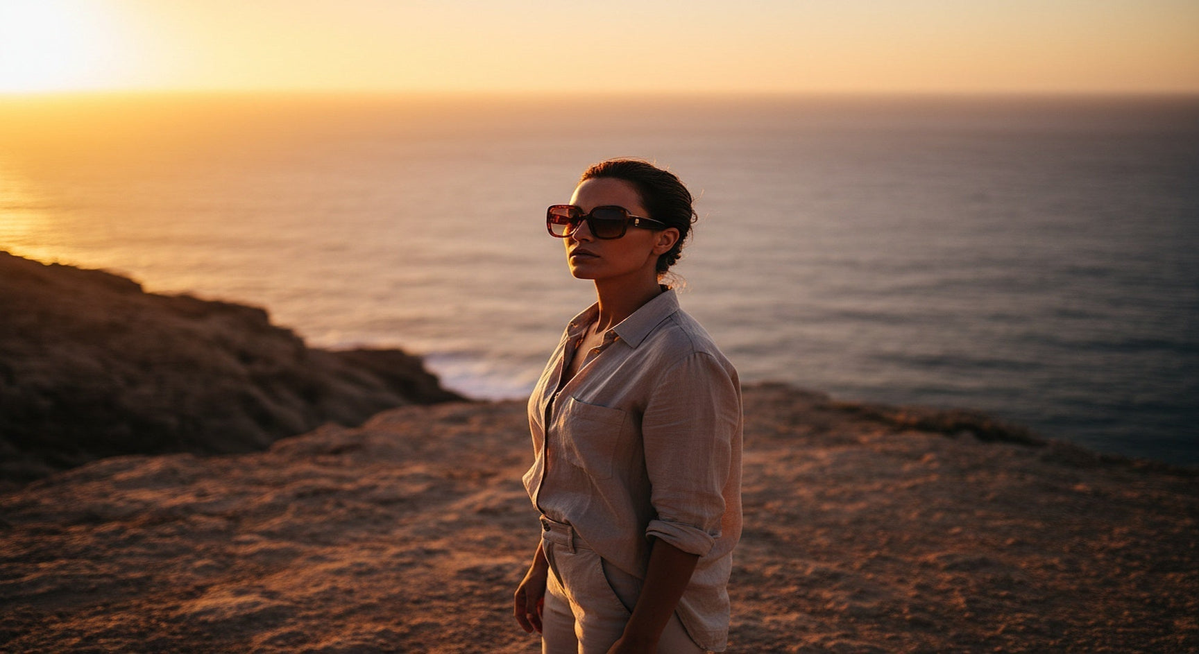 Person on coastal cliff wearing amber tinted glasses at golden hour — tinted glasses colors for outdoor wear