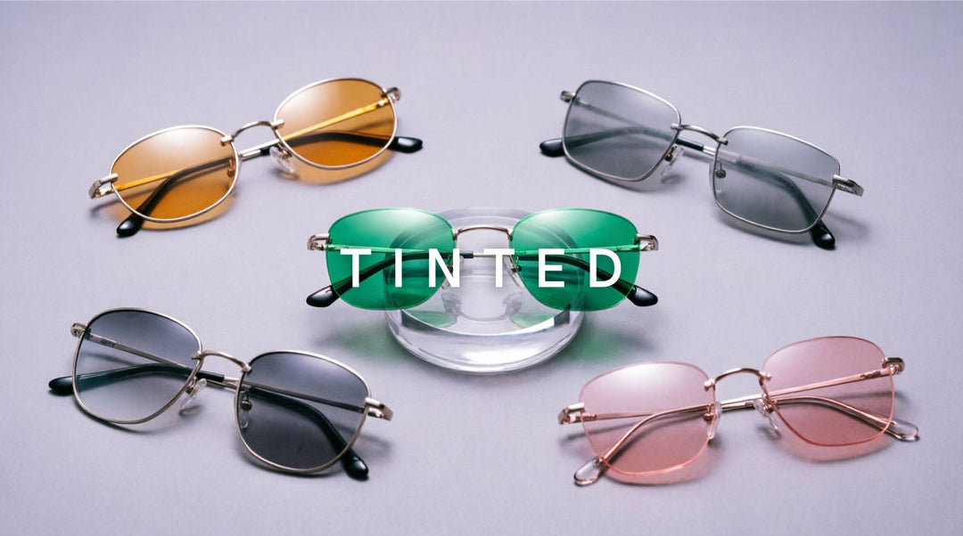 FuzWeb Tinted collection featuring rimless stainless steel alloy eyeglasses with amber gray emerald rose progressive single vision tinted lenses on lavender-gray studio background with soft diffused lighting