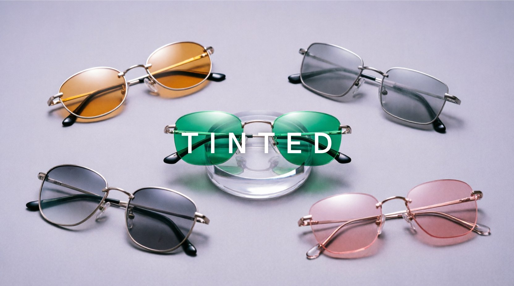 FuzWeb Tinted collection featuring rimless stainless steel alloy eyeglasses with amber gray emerald rose progressive single vision tinted lenses on lavender-gray studio background with soft diffused lighting