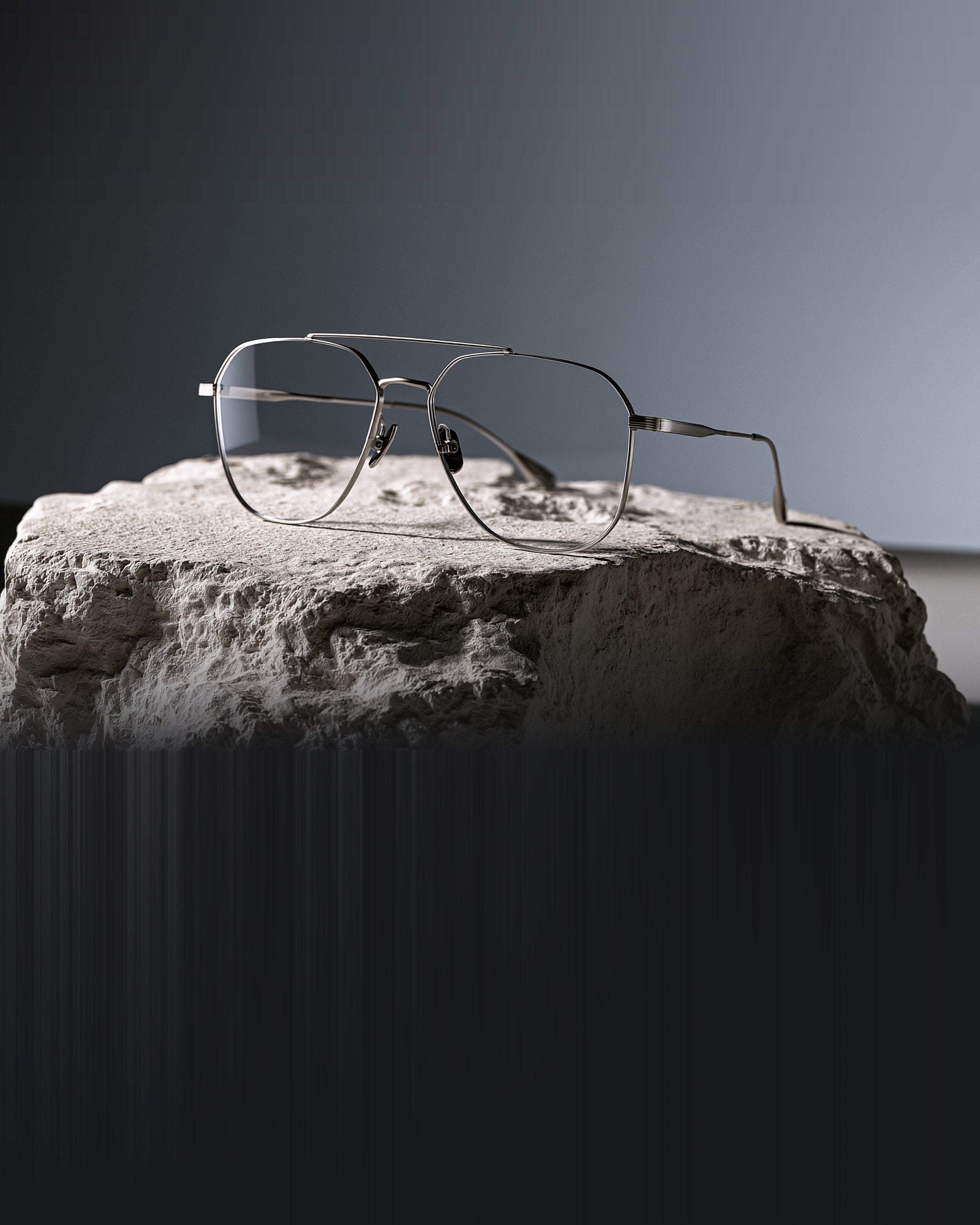 Titanium aviator prescription eyeglasses resting on a stone block
